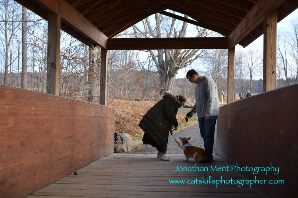 Couple bending over dog on covered bridge